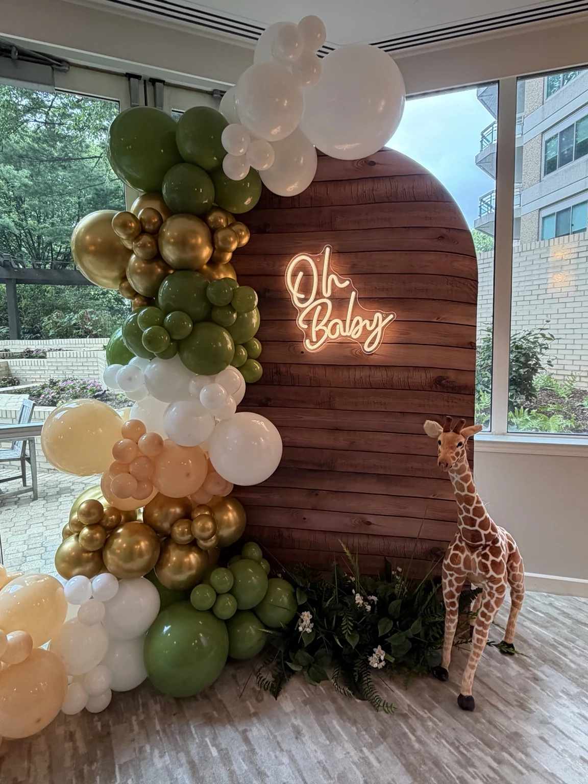 Safari Oh Baby backdrop with green, white, peach and gold balloons and giraffe decoration
